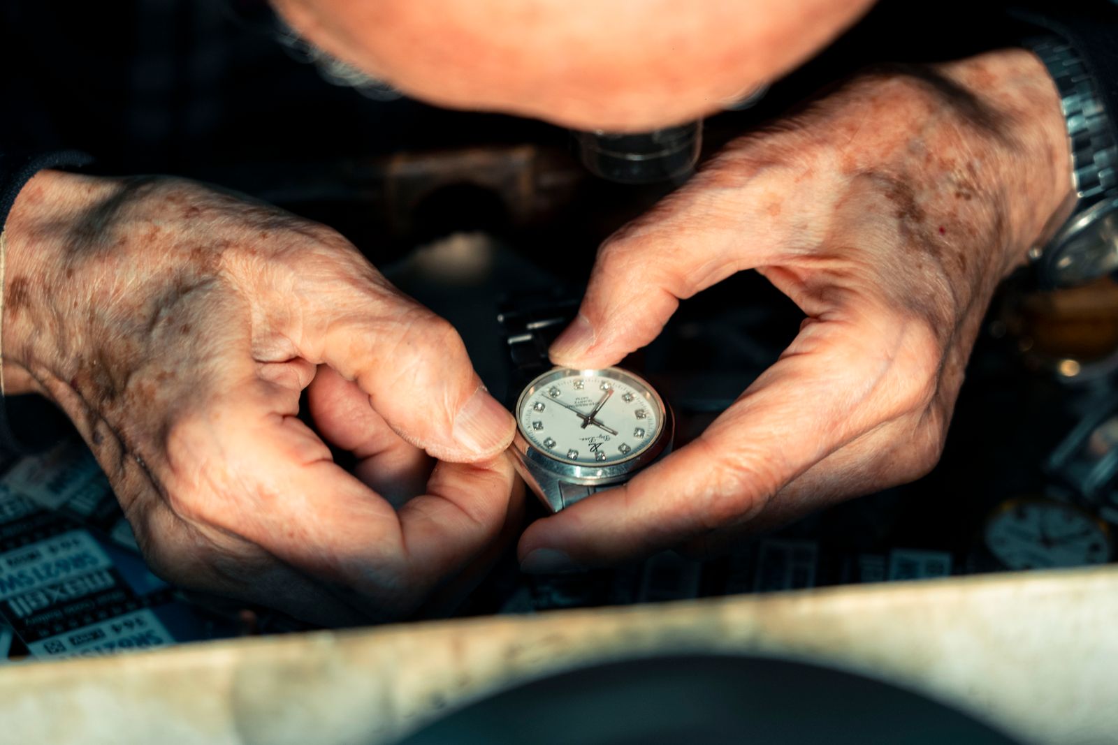 A watchmaker inspects a wristwatch through a loupe