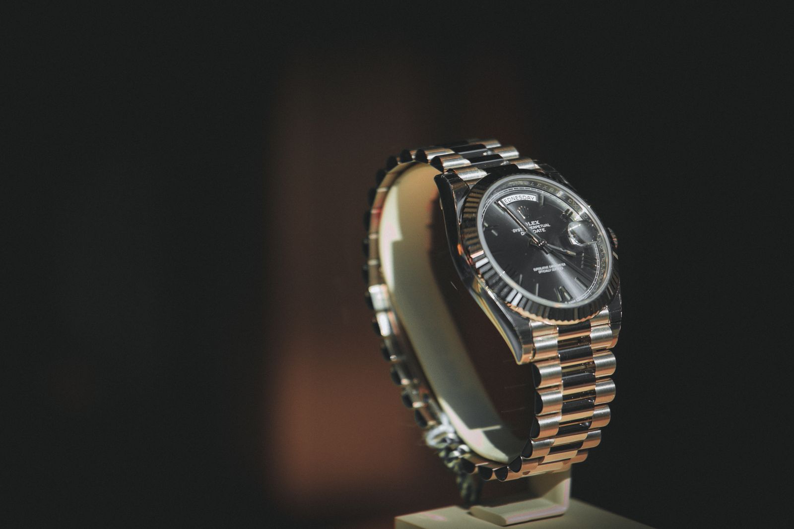 A Day-Date style gold watch on a display stand